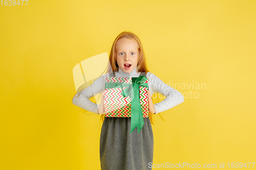 Image of Giving and getting presents on Christmas holidays. Teen girl having fun isolated on yellow studio background