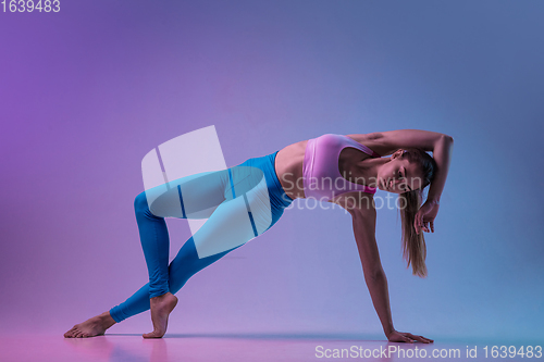 Image of Young sportive woman training isolated on gradient studio background in neon light. athletic and graceful