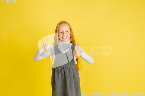 Image of Portrait of little caucasian girl with bright emotions isolated on yellow studio background