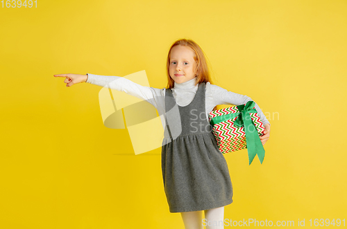 Image of Giving and getting presents on Christmas holidays. Teen girl having fun isolated on yellow studio background