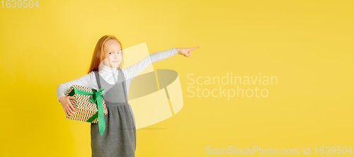 Image of Giving and getting presents on Christmas holidays. Teen girl having fun isolated on yellow studio background