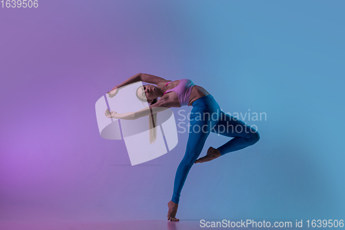Image of Young sportive woman training isolated on gradient studio background in neon light. athletic and graceful