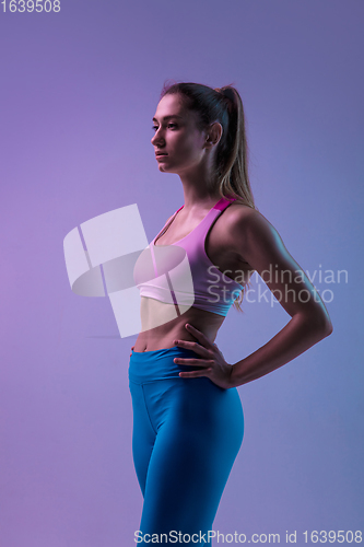 Image of Young sportive woman training isolated on gradient studio background in neon light. athletic and graceful