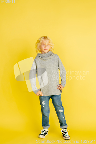 Image of Portrait of little caucasian boy with bright emotions isolated on yellow studio background