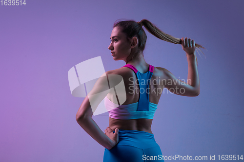 Image of Young sportive woman training isolated on gradient studio background in neon light. athletic and graceful