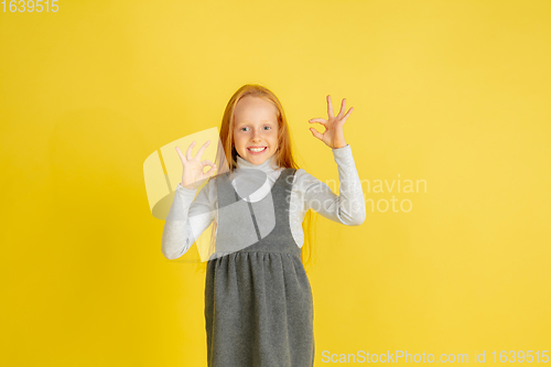 Image of Portrait of little caucasian girl with bright emotions isolated on yellow studio background
