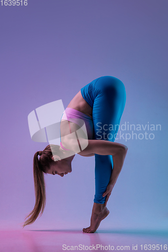 Image of Young sportive woman training isolated on gradient studio background in neon light. athletic and graceful