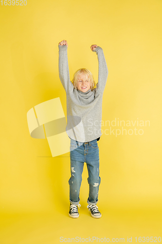 Image of Portrait of little caucasian boy with bright emotions isolated on yellow studio background