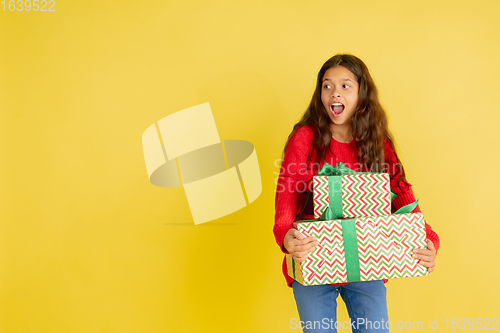 Image of Giving and getting presents on Christmas holidays. Teen girl having fun isolated on yellow studio background