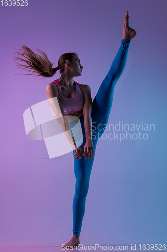 Image of Young sportive woman training isolated on gradient studio background in neon light. athletic and graceful