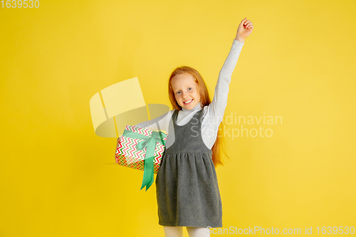 Image of Giving and getting presents on Christmas holidays. Teen girl having fun isolated on yellow studio background