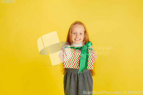 Image of Giving and getting presents on Christmas holidays. Teen girl having fun isolated on yellow studio background