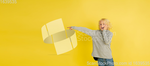 Image of Portrait of little caucasian boy with bright emotions isolated on yellow studio background