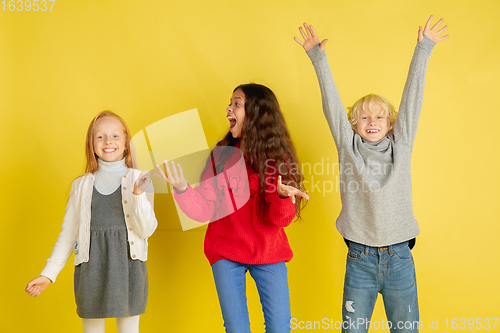 Image of Portrait of little caucasian children with bright emotions isolated on yellow studio background