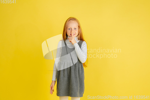 Image of Portrait of little caucasian girl with bright emotions isolated on yellow studio background