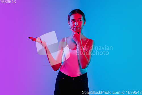 Image of Young caucasian woman\'s portrait on gradient blue-purple studio background in neon light