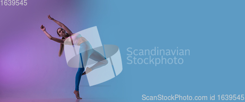 Image of Young sportive woman training isolated on gradient studio background in neon light. athletic and graceful