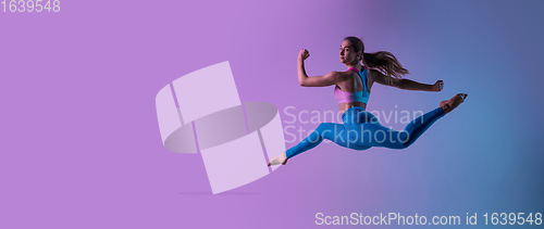 Image of Young sportive woman training isolated on gradient studio background in neon light. athletic and graceful