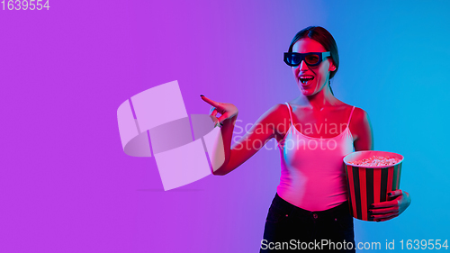 Image of Young caucasian woman\'s portrait on gradient blue-purple studio background in neon light