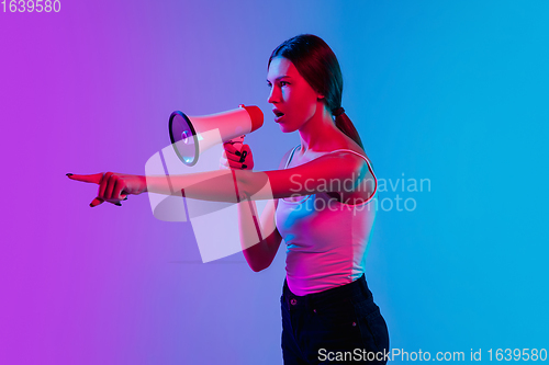 Image of Young caucasian woman\'s portrait on gradient blue-purple studio background in neon light