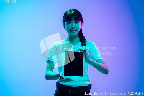 Image of Young asian woman\'s portrait on gradient blue-purple studio background in neon light