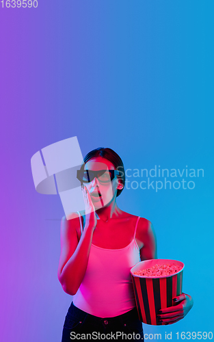 Image of Young caucasian woman\'s portrait on gradient blue-purple studio background in neon light