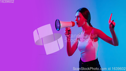 Image of Young caucasian woman\'s portrait on gradient blue-purple studio background in neon light