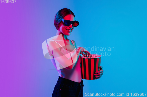 Image of Young caucasian woman\'s portrait on gradient blue-purple studio background in neon light