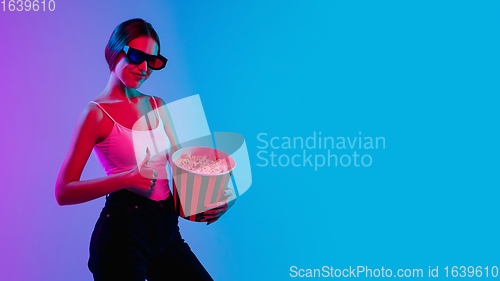 Image of Young caucasian woman\'s portrait on gradient blue-purple studio background in neon light