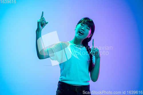Image of Young asian woman\'s portrait on gradient blue-purple studio background in neon light