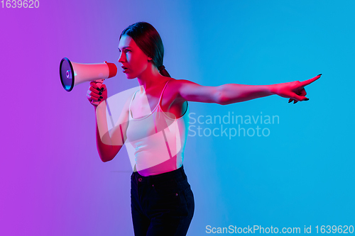 Image of Young caucasian woman\'s portrait on gradient blue-purple studio background in neon light