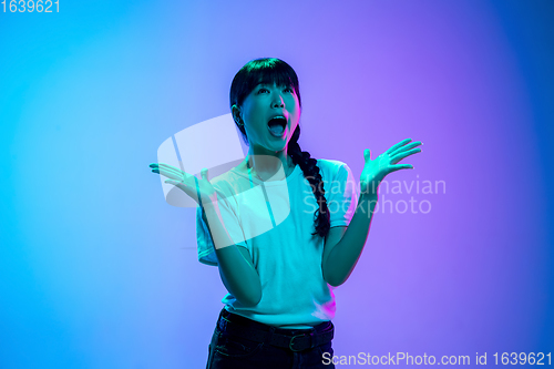 Image of Young asian woman\'s portrait on gradient blue-purple studio background in neon light