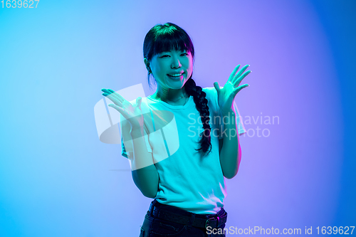 Image of Young asian woman\'s portrait on gradient blue-purple studio background in neon light