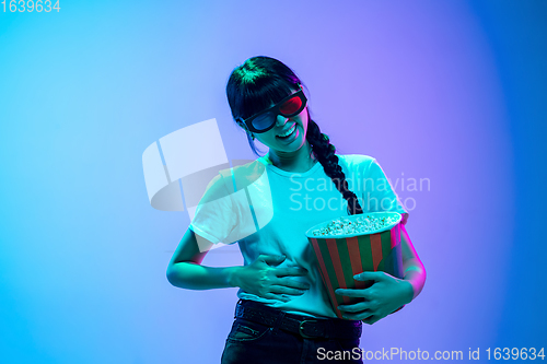 Image of Young asian woman\'s portrait on gradient blue-purple studio background in neon light