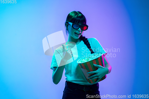 Image of Young asian woman\'s portrait on gradient blue-purple studio background in neon light