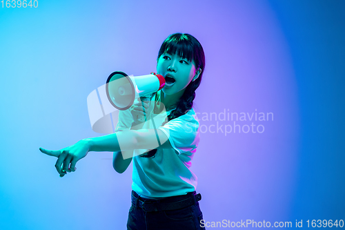 Image of Young asian woman\'s portrait on gradient blue-purple studio background in neon light