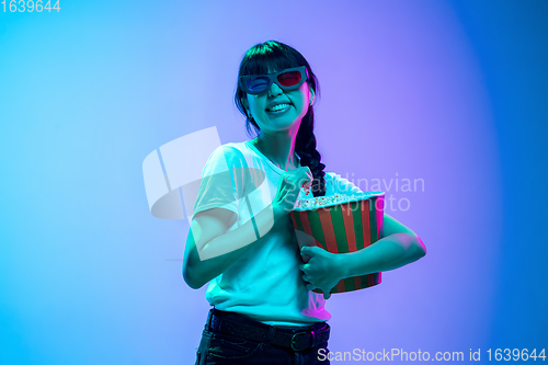 Image of Young asian woman\'s portrait on gradient blue-purple studio background in neon light