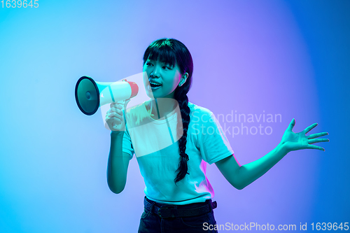 Image of Young asian woman\'s portrait on gradient blue-purple studio background in neon light