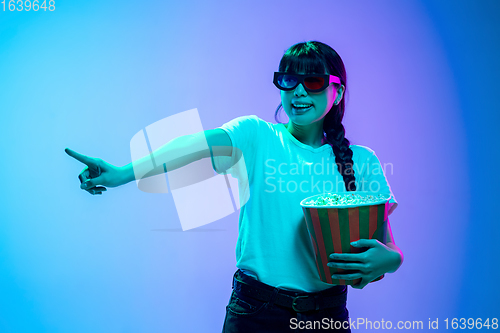 Image of Young asian woman\'s portrait on gradient blue-purple studio background in neon light