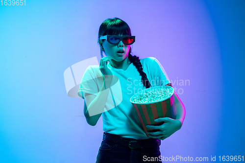 Image of Young asian woman\'s portrait on gradient blue-purple studio background in neon light