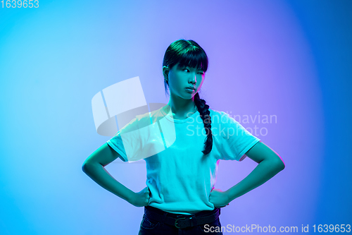 Image of Young asian woman\'s portrait on gradient blue-purple studio background in neon light