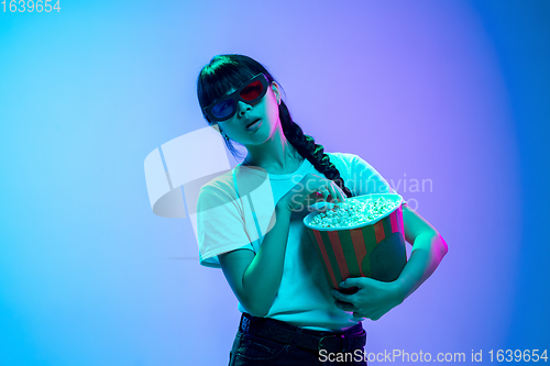 Image of Young asian woman\'s portrait on gradient blue-purple studio background in neon light