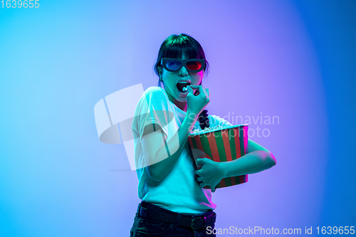 Image of Young asian woman\'s portrait on gradient blue-purple studio background in neon light