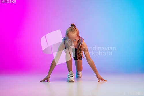 Image of Teenage girl running, jogging against gradient pink-blue neon studio background in motion