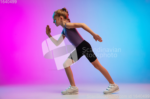 Image of Teenage girl running, jogging against gradient pink-blue neon studio background in motion