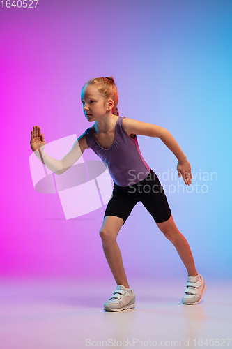 Image of Teenage girl running, jogging against gradient pink-blue neon studio background in motion