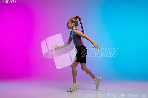 Image of Teenage girl running, jogging against gradient pink-blue neon studio background in motion