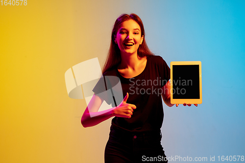 Image of Young caucasian woman\'s portrait on gradient blue-yellow studio background in neon light