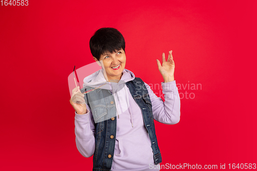 Image of Senior woman isolated on red background. Tech and joyful elderly lifestyle concept