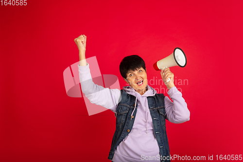 Image of Senior woman isolated on red background. Tech and joyful elderly lifestyle concept